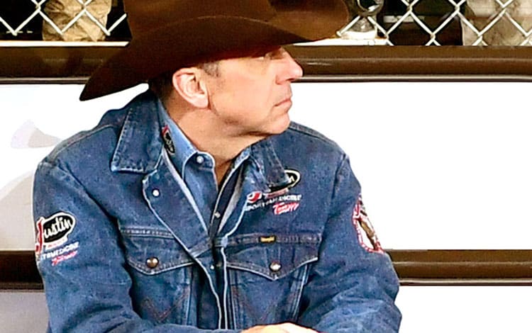 Man in cowboy hat and jean jacket looks into the distance 